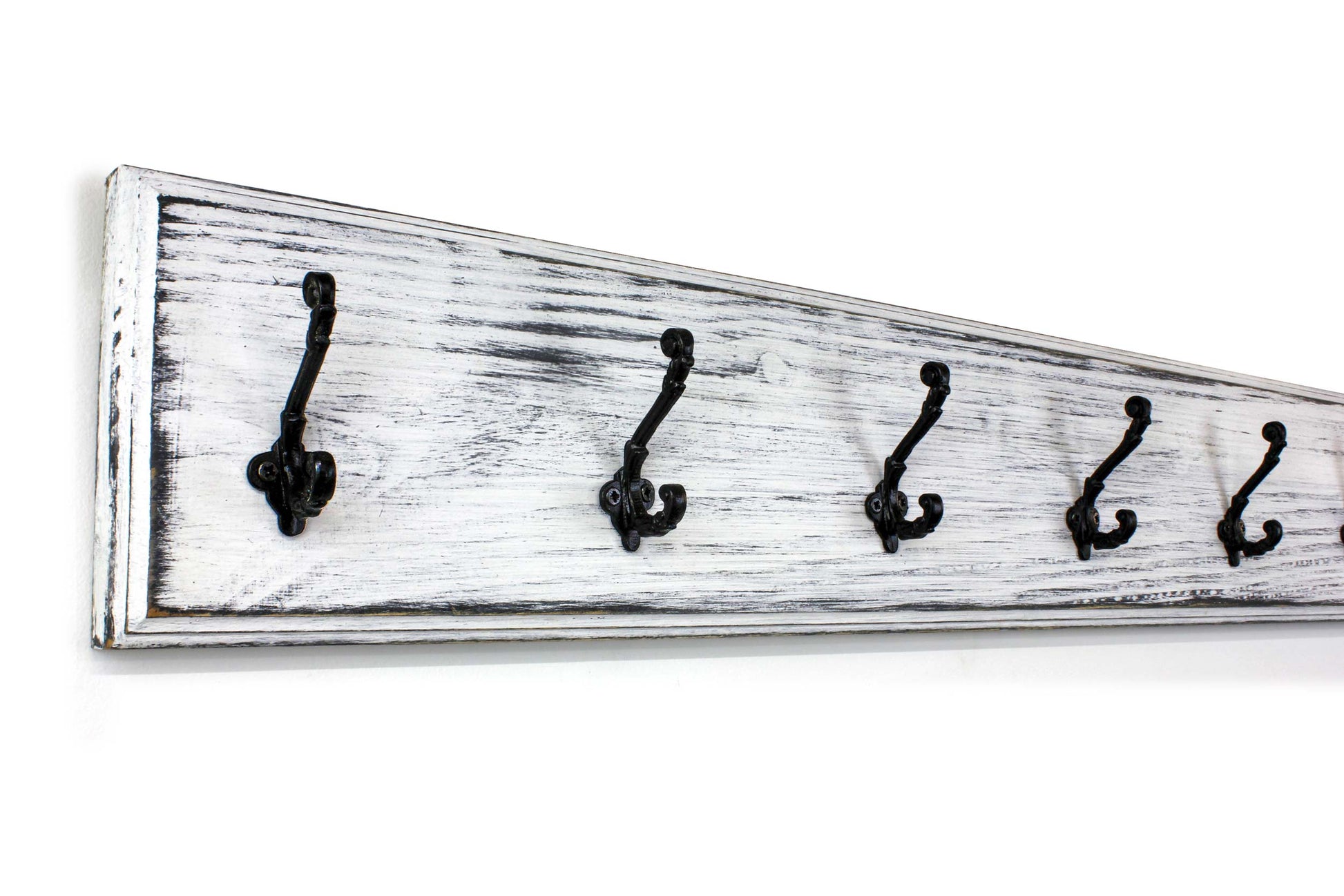 Close-up of handcrafted wooden coat rack with dark metal wall hooks and natural wood grain shows through at the edges of the distressed white paint over black. Farmhouse-style design with high-quality hardware. Durable and stylish wall-mounted organizer for home or office use.