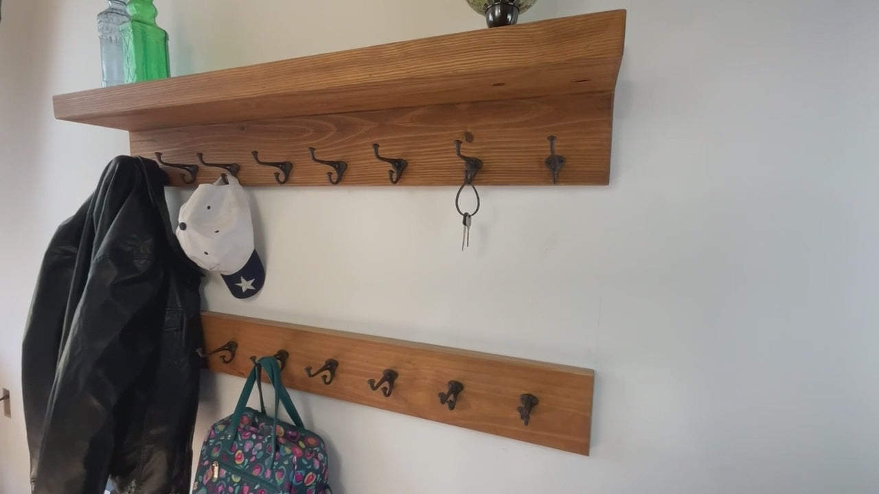rustic coat rack with  dark metal hooks mounted on a stained wooden board. The nailhead vintage hooks have a curved design and are attached with screws. The wood grain is visible, adding to the natural aesthetic.