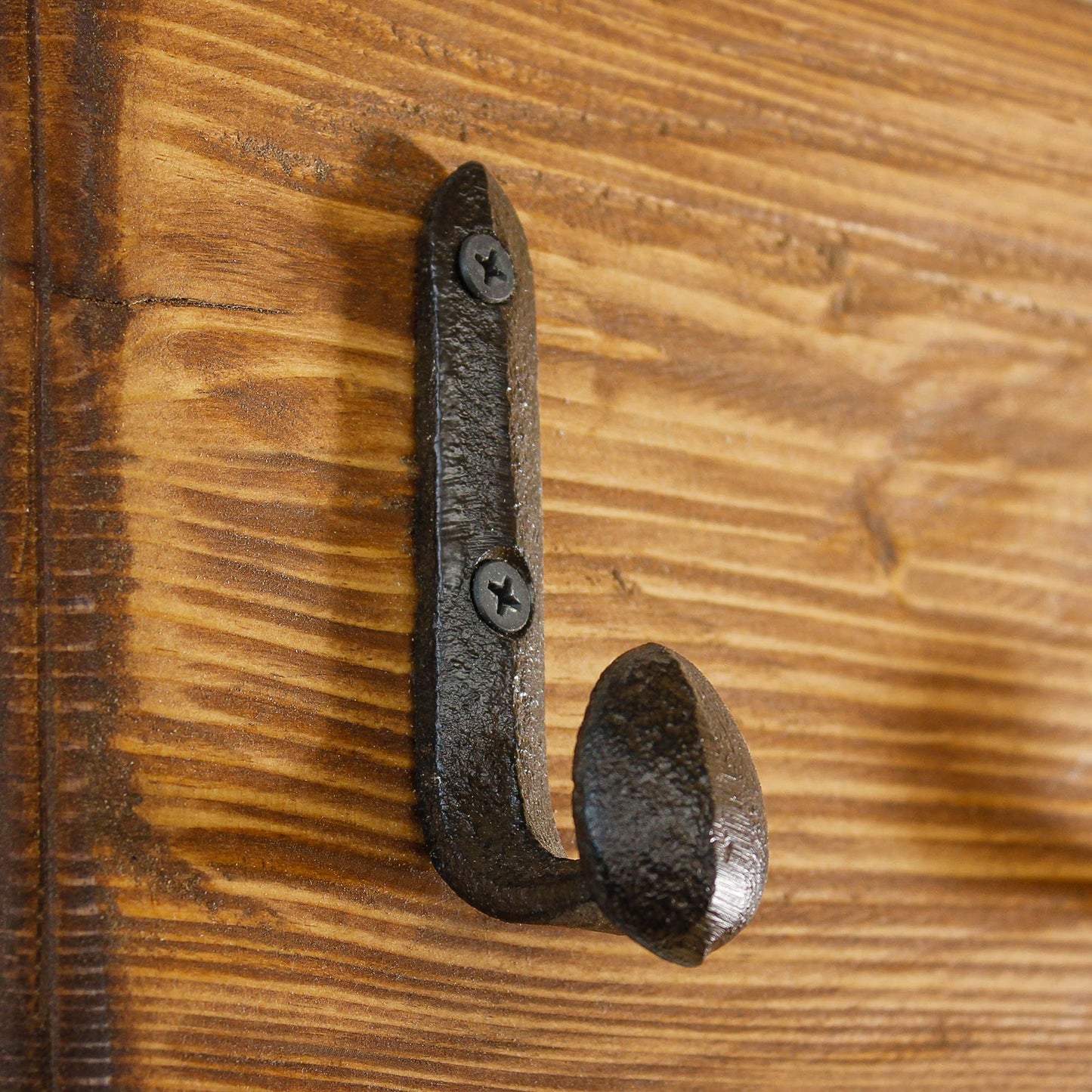 Single rustic railroad spike hook mounted on a natural wood plank for a farmhouse coat rack.