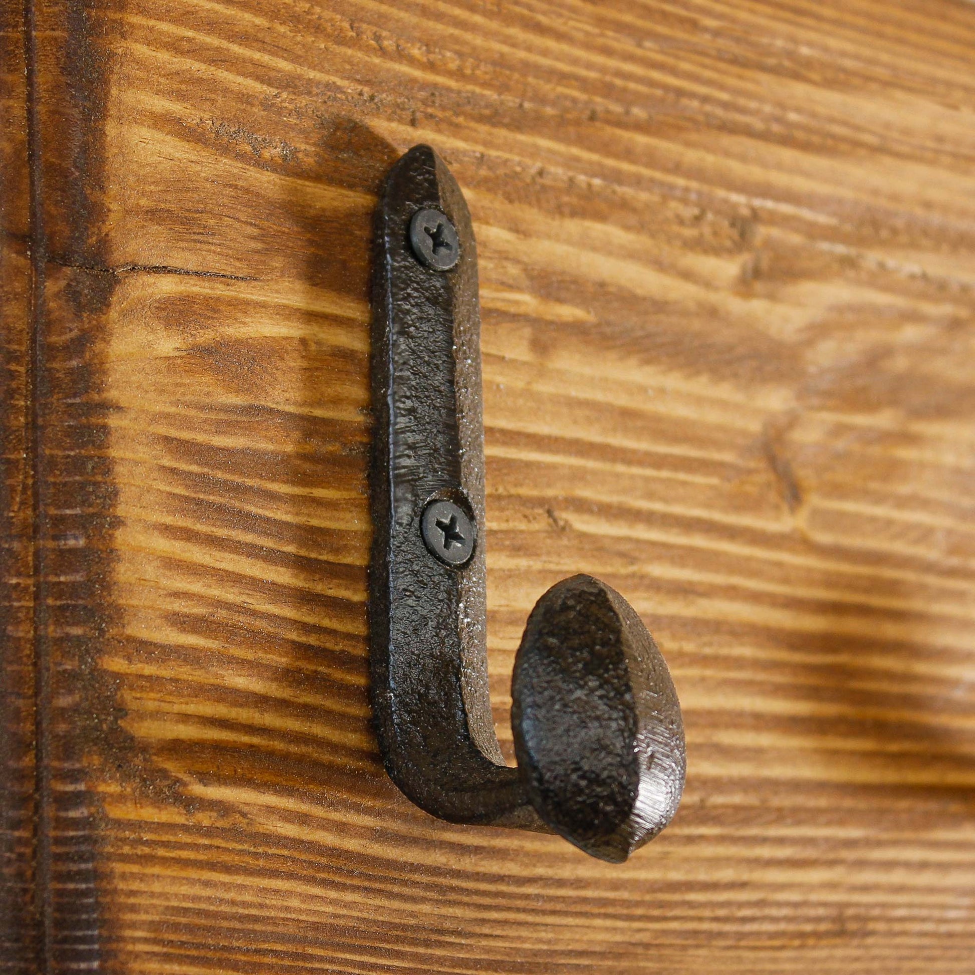 Single rustic railroad spike hook mounted on a natural wood plank for a farmhouse coat rack.