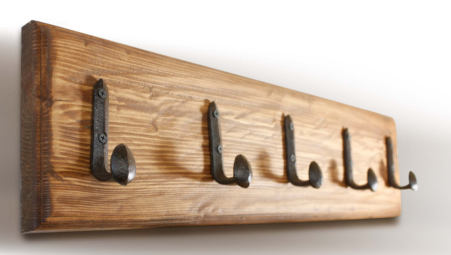 Industrial railroad spike hook holding a heavy backpack in a rustic mudroom entryway.